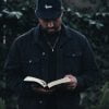 man in black jacket holding book